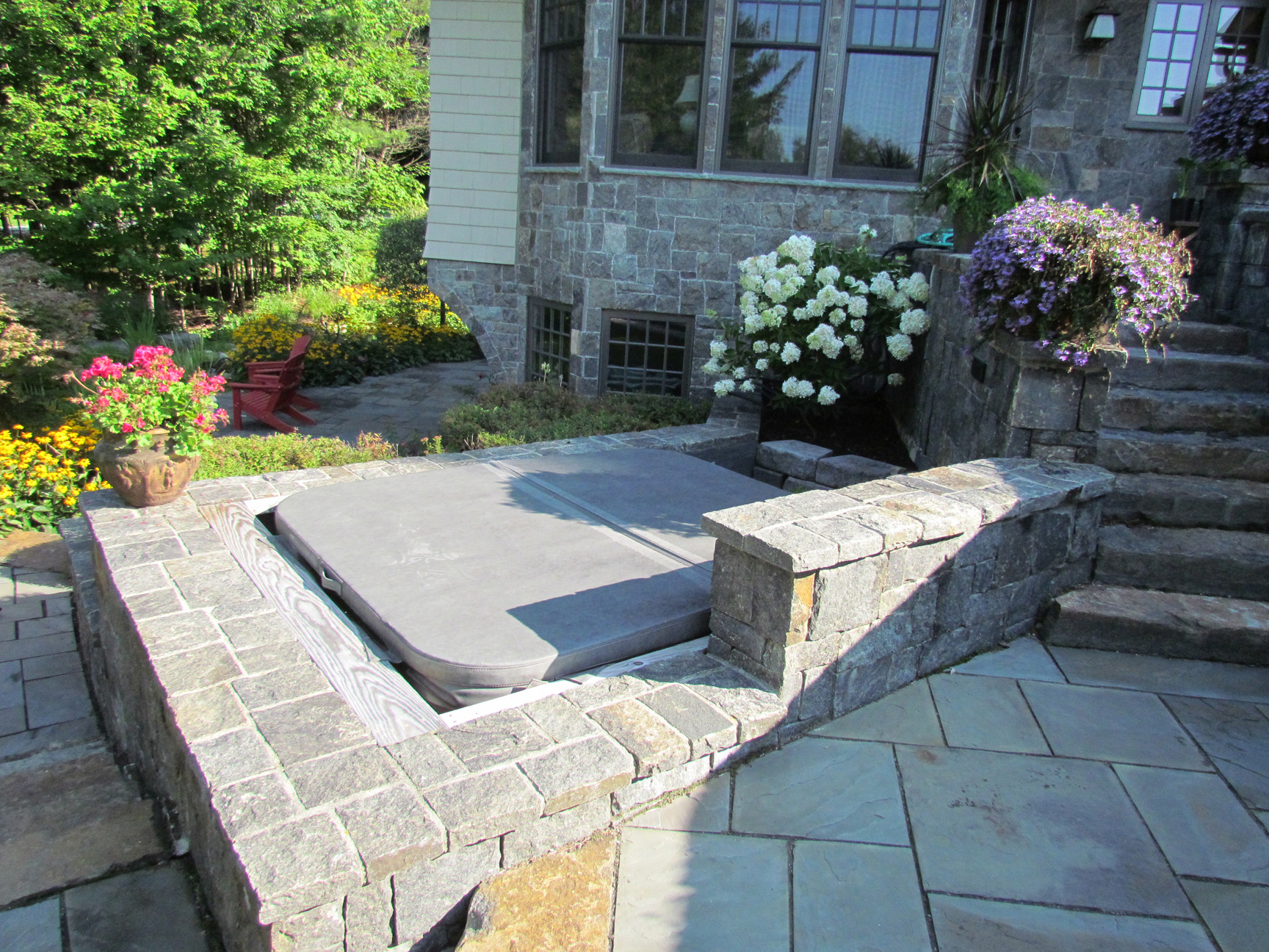 Tucked away hot tub finished with stone surround by Carpenter & Costin